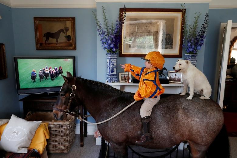 Merlin Coles 3, watches the horse racing from Royal Ascot on TV at his home, whilst sat on his horse Mr Glitter Sparkles with his dog Mistress, in Bere Regis, Dorset, Britain.  REUTERS/Paul Childs  